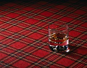 Ein Glas Malt-Whisky auf kariertem Schotten-Tuch (Tartan)