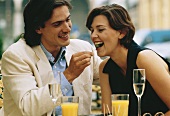 Couple at a street café eating olives, half-length picture