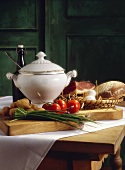 Rustic still life with soup pot, vegetables, bread & bacon