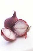 One whole and one halved red onion on white background