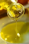 Olivenöl in dünnem Strahl auf einen Teller gießen