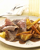 Slices of roast beef with gravy and roasted vegetables