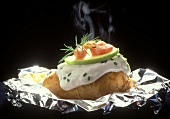 Baked potato on aluminium foil with quark and shrimps