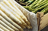Green and white asparagus spears in front of and in a crate