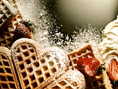 Waffeln mit Puderzucker, dekoriert mit Erdbeeren & Sahne