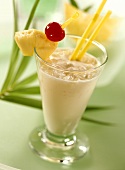 Pina Colada in glass garnished with pineapple, cherry, straws
