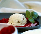 A scoop of Malaga ice cream with raspberry sauce & mint leaves