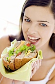 Young woman eating giant sandwich