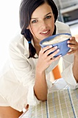 Junge Frau trinkt Milchkaffee aus Schälchen