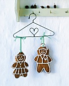 Two gingerbread figures hanging on a wire coat-hanger