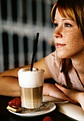 Sommersprossige junge Frau mit Latte Macchiato