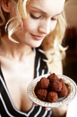 Young woman holding plate of rum truffles