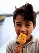 Boy eating passion fruit ice cream on a stick