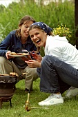 Zwei junge Frauen beim Grillen im Freien