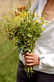 Woman holding bunch of meadow flowers