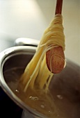Gekochte Spaghetti mit Holzlöffel aus dem Kochwasser heben