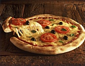 Pizza Margherita auf Holzuntergrund, Stück auf Pizzaheber