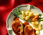Schweinebraten mit Sosse und Gemüse auf weißem Teller