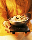 Hand holding wooden tray with rice bowl