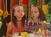 Two girls blowing out candles on birthday cake