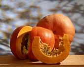 Zwei orangefarbenen Speisekürbisse, einer angeschnitten