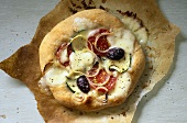 Minipizza mit Gemüse und Käse auf Backpapier