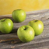 Vier Äpfel der Sorte Granny Smith auf Holzuntergrund