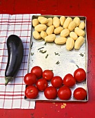 Potatoes & tomatoes on a baking tray, aubergine beside it