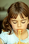 Small girl eating spaghetti with tomato sauce