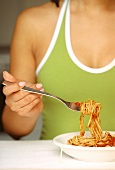 Woman eating spaghetti with tomato sauce