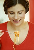 Woman holding forkful of spaghetti and tomato sauce