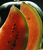 Zwei Wassermelonenscheiben vor ganzer Melone