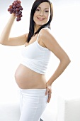 Pregnant woman holding red grapes in her hand