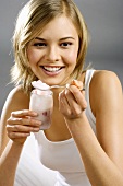 Young woman with yoghurt jar and spoon