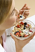 Young woman eating muesli with fresh fruit and natural yoghurt