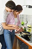 Young couple frying vegetables in wok