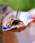Woman at picnic holding herring with tomato and dill