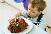 Kleiner Junge an Geburtstagskuchen naschend