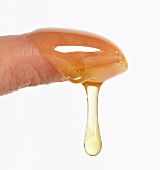 Honig tropft von einem Finger (Nahaufnahme)