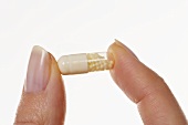 Vitamin pill between two fingers