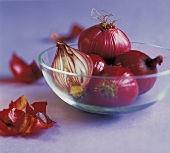 Several red onions in a glass dish