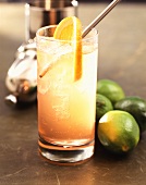 Orange and gin drink with limes and cocktail shaker