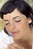 Young woman smelling a cornflower