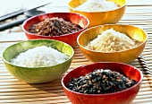Several types of rice in five coloured bowls