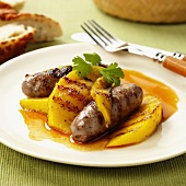 Two sausages with grilled mango slices