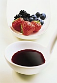 Fruit syrup on ladle in front of fresh berries