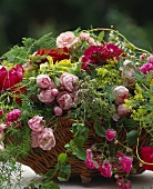 Korb mit Rosen in verschiedenen Rottönen und Zierspargel