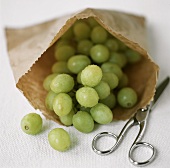 Green grapes in paper bag and a pair of scissors