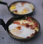 Eggs and bacon in two small frying pans