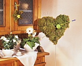 White rose in pot & Gerbera on sideboard, moss heart with arrow